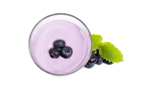 Blueberries on milkshake next to blueberries on white background