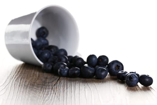 Blueberries rolling out of upside-down cup with backlight