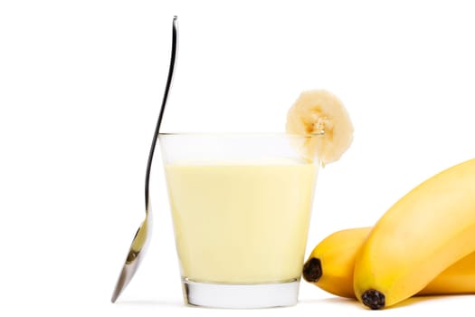 Bananas milkshake with spoon and bananas next to it on white background