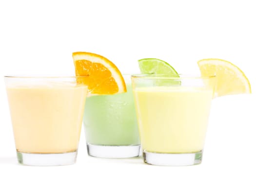 Three cold citrus milkshakes on white background