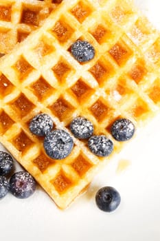 Waffles with sugared blueberries and syrup on white background