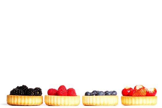 Set of tartlet cakes with wild berries on white background