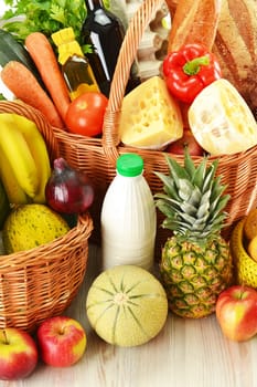 Groceries in wicker basket isolated on white