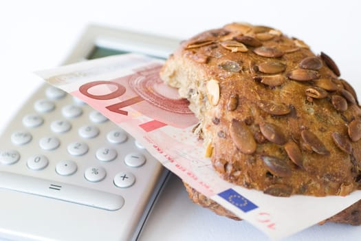 Bread roll with ten euro bill and calculator