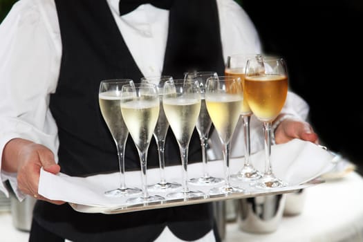 Waiter serves champagne and wine - in the foreground are the champagne and wine glasses on a tray.