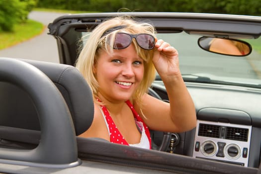 Young blonde woman at the wheel of a convertible