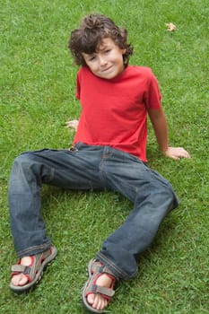 Happy child sitting on the grass with red shirt