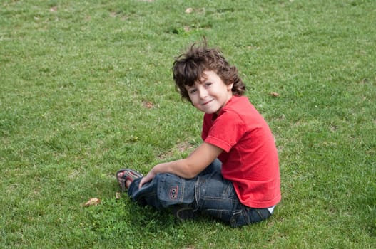 Happy child sitting on the grass with red shirt