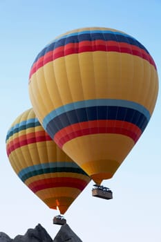 Low level flying over Cappadocia peaks by two identical hot air balloons, Cappadocia, sky blue sky, limestone peqks, portrait, crop space, copy space