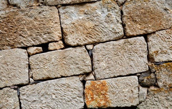Dry walling in Cappadocia at an angle, Turkey. Random limestone bricks, manually surfcace etched, yellow petaled weed, landscape, copy space with crop space