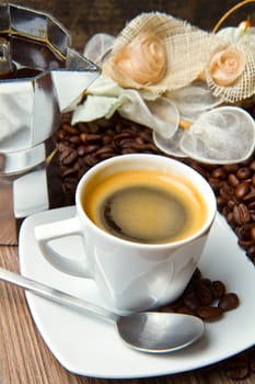 Coffee cup with burlap sack of roasted beans on rustic table