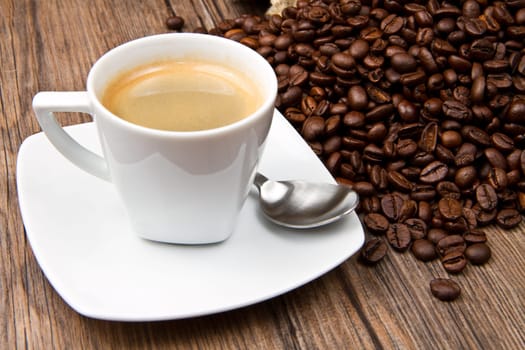 Coffee cup with burlap sack of roasted beans on rustic table