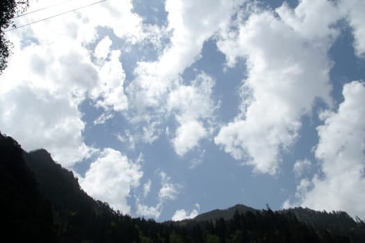 Bright dazzling clouds with dark mountain in foreground