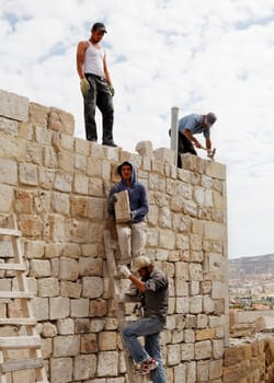 Goreme, Cappadocia, Turkey - June, 2011: Men at work, building bricks teamwork on a ladder Turkish builders