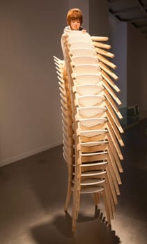 Istanbul, Turkey - June, 2011: Boy climbing chairs sculpture by Patricia Piccinini art show at Arter Gallery