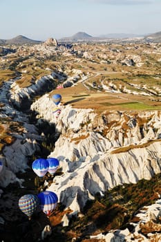 Cappadocia, Turkey - June, 2011: hot air balloons sailing the edges of a ravine
