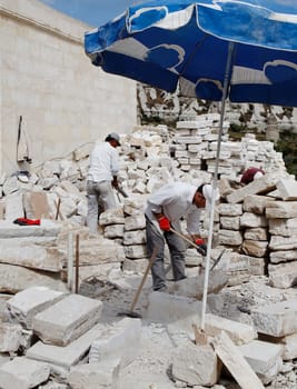 Goreme, Cappadocia, Turkey - June, 2011: Men at work, Turkish builders protected from hot sun by shade of parasol