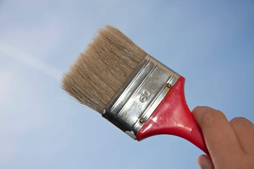 Hand holding flat brush in the sky