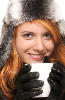 Portrait of a young redhead woman in winter clothes and a coffee cup against a white background