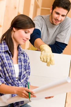 Home improvement happy young couple with architectural blueprints fixing house