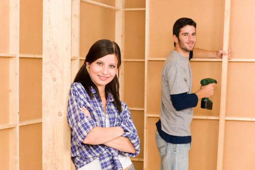 Home improvement smiling young couple fixing wall with hand drill