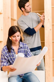 Home improvement happy young couple with architectural blueprints fixing house