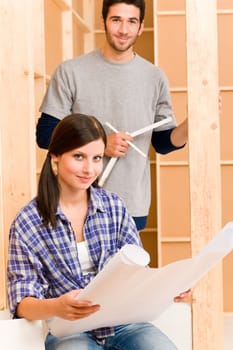 Home improvement happy young couple with architectural blueprints fixing house