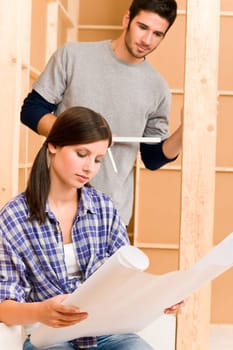 Home improvement happy young couple with architectural blueprints fixing house