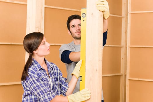 Home improvement smiling young couple fixing wall with spirit level