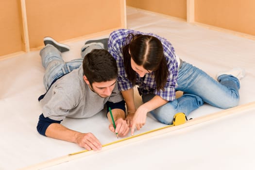 Home improvement young couple working on floor renovations measure rule