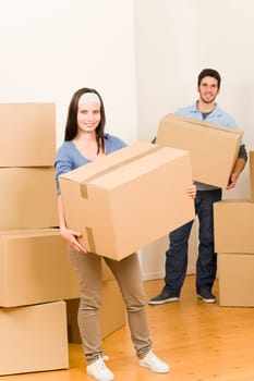 Happy young couple moving into new home carrying cardboard boxes