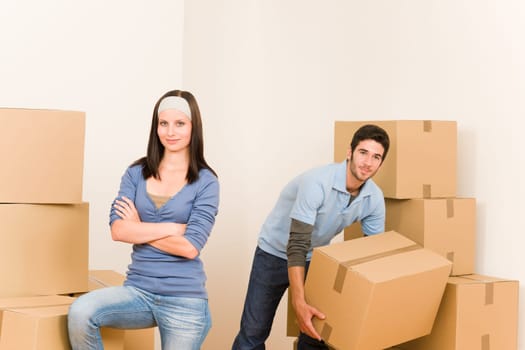 Happy young couple moving into new home carrying cardboard boxes