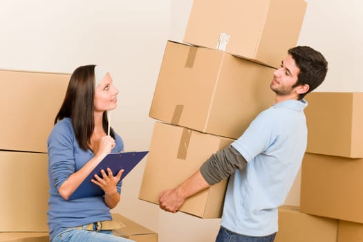 Happy young couple moving into new home carrying cardboard boxes