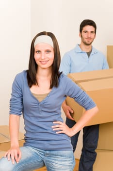 Happy young couple moving into new home carrying cardboard boxes