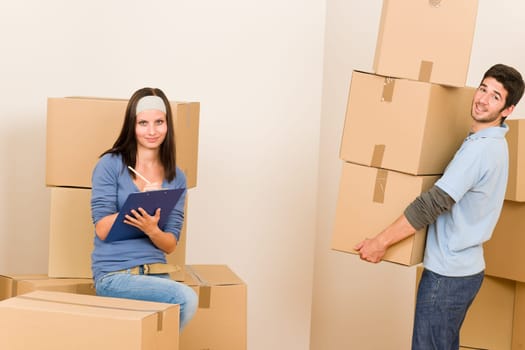 Happy young couple moving into new home carrying cardboard boxes