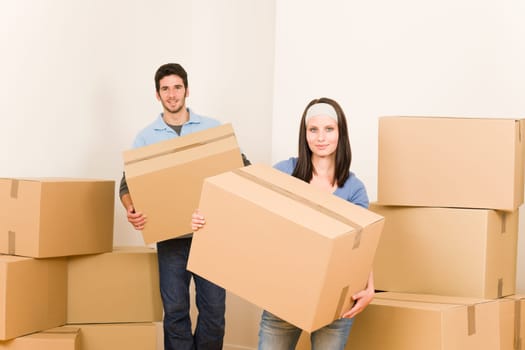 Happy young couple moving into new home carrying cardboard boxes