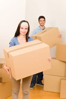 Happy young couple moving into new home carrying cardboard boxes
