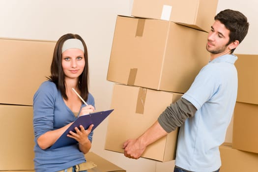 Happy young couple moving into new home carrying cardboard boxes