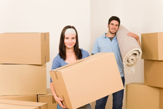 Happy couple with boxes and carpet moving into new home