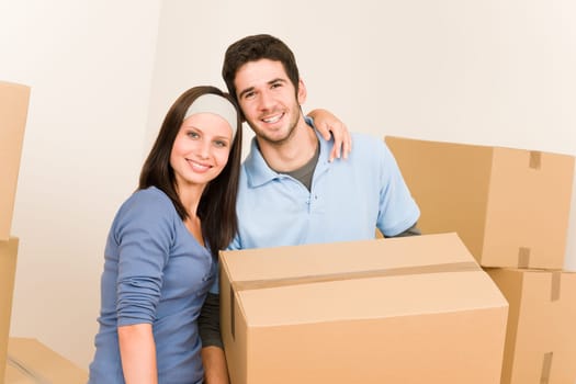 Happy young couple moving into new home carrying cardboard boxes