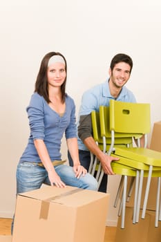 Moving into new home young happy couple carry chairs