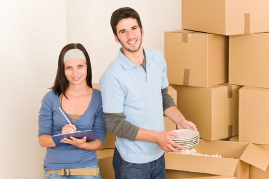 Moving new home young happy couple unpacking cardboard boxes together