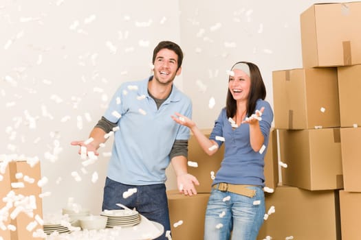 Moving home young cheerful couple throw Styrofoam peanuts unpacking boxes