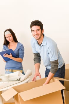 Moving new home young happy couple unpacking cardboard boxes together