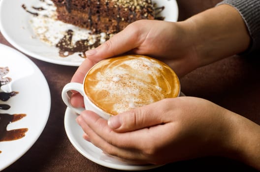 Closeup of female hands holding cup of Cappuccino