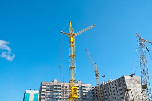 Building crane and building under construction against blue sky