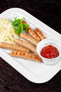 Grilled sausages with cabbage, greens and tomato sauce on white plate
