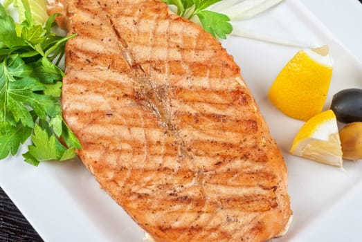 Grilled salmon steak with greens,onion, lemon, lime and olive