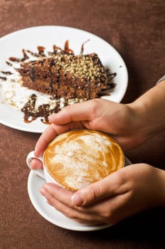 Closeup of female hands holding cup of Cappuccino