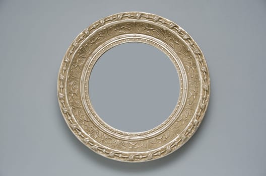 Picture gold frame with a decorative pattern on a gray wall